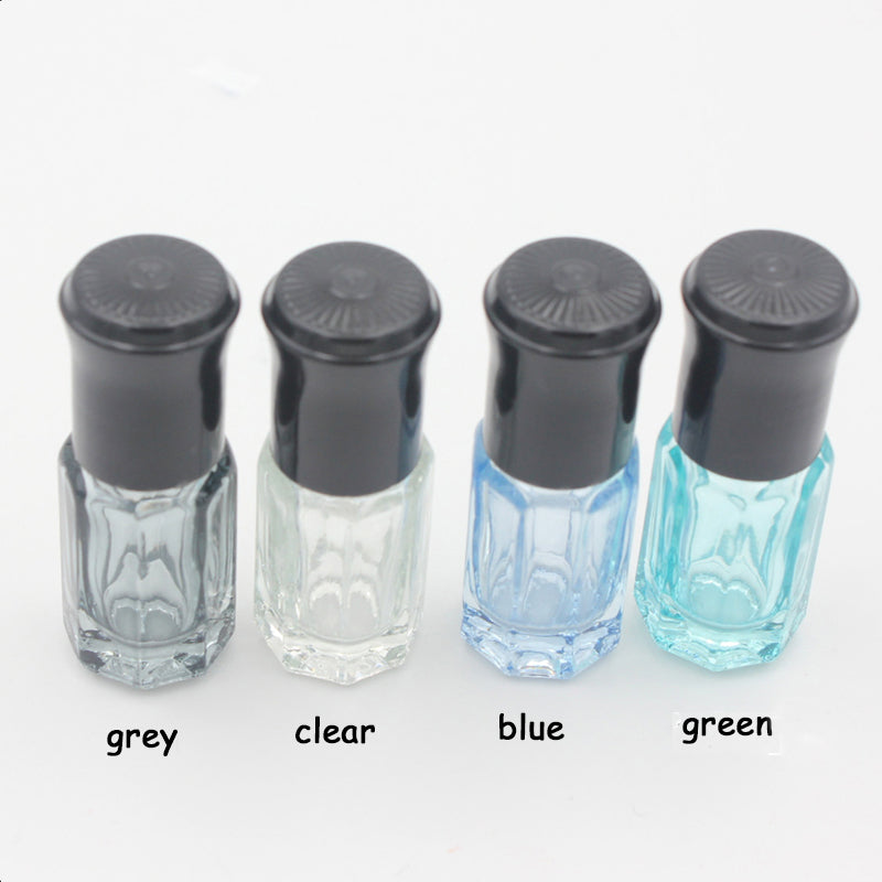 Four colorful essential oil roller bottles in grey, clear, blue, and green with black caps.